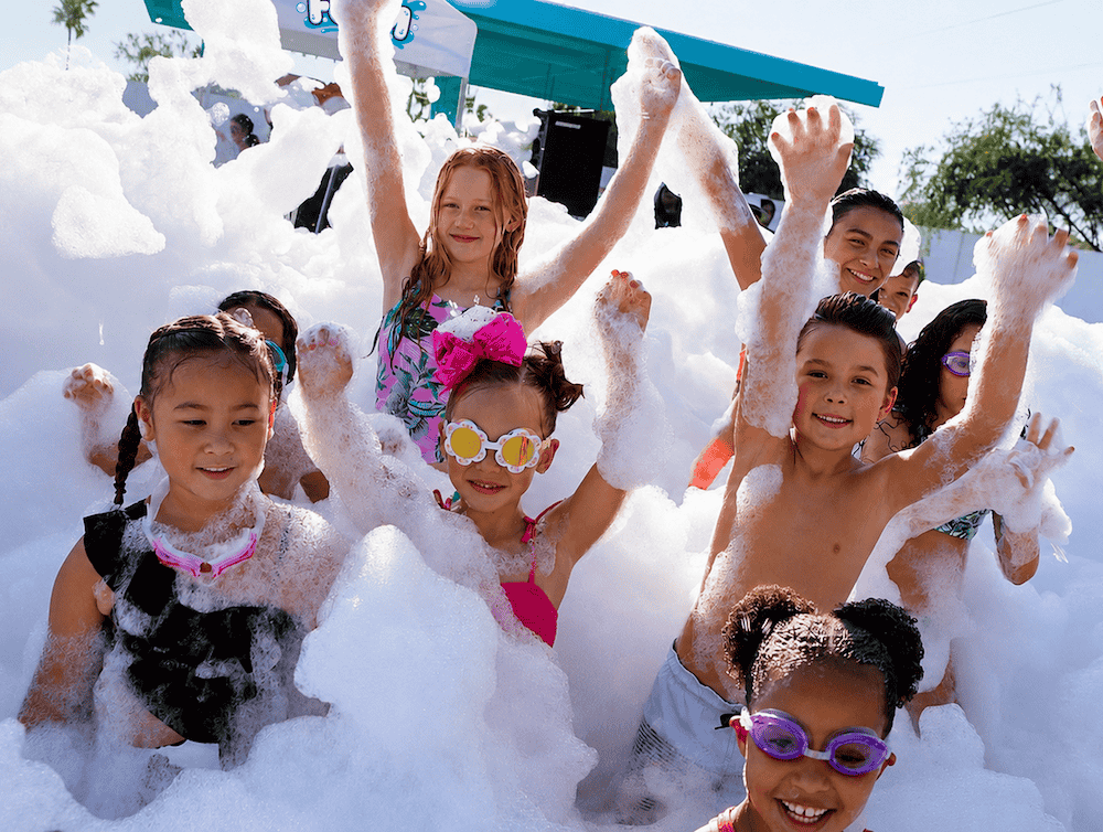 Children playing and dancing in giant foam bubbles during a Fun Foam Party birthday party in Michigan with music, beach balls, and professional entertainment.